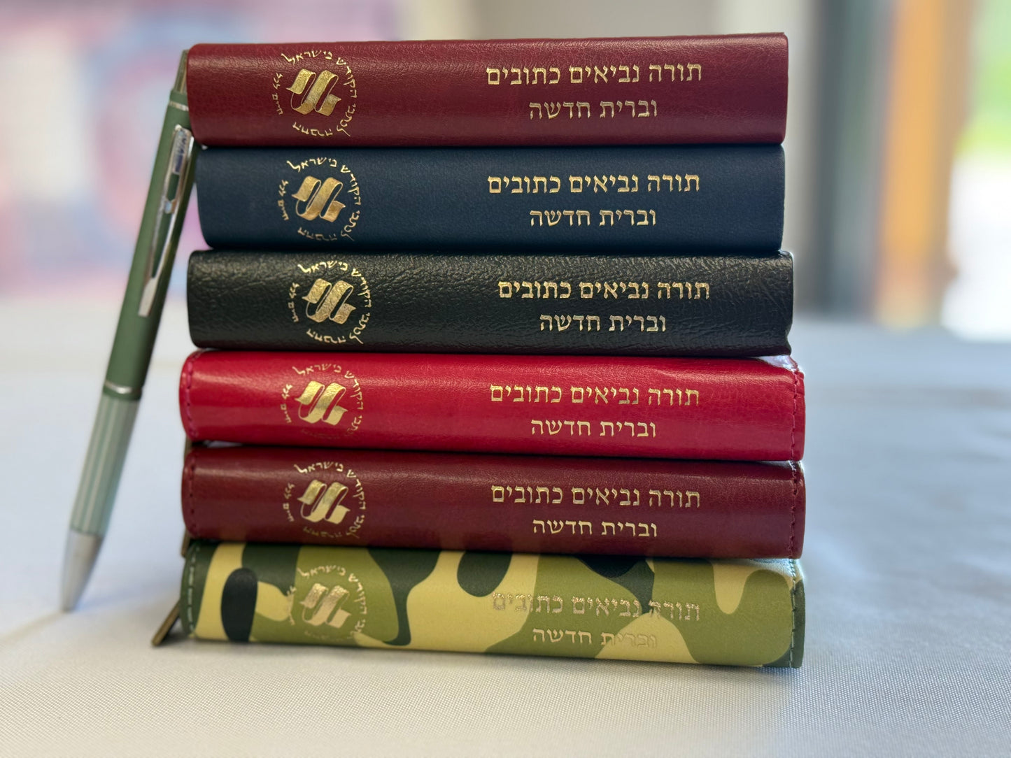 Stack of six Hebrew pocket Bibles next to a pen