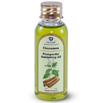 A bottle of Cinnamon Prosperity Anointing Oil with a label showing the product name and an illustration of cinnamon sticks.