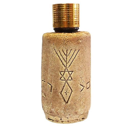 A beige ceramic anointing oil bottle with an embossed grafted in symbol, topped with a brass cap.