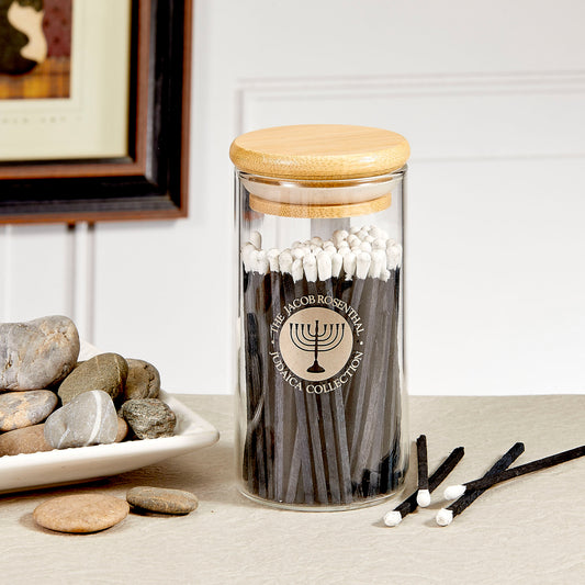 A Glass match holder that contains 75 blue wood and white tipped matches sitting on a table.