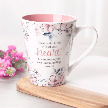 White cone-shaped coffee mug with a pink floral design and the Scripture “Trust in the LORD” on the front