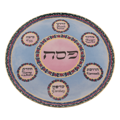 Pink and blue seder plate with a floral design and yellow trim around the edges