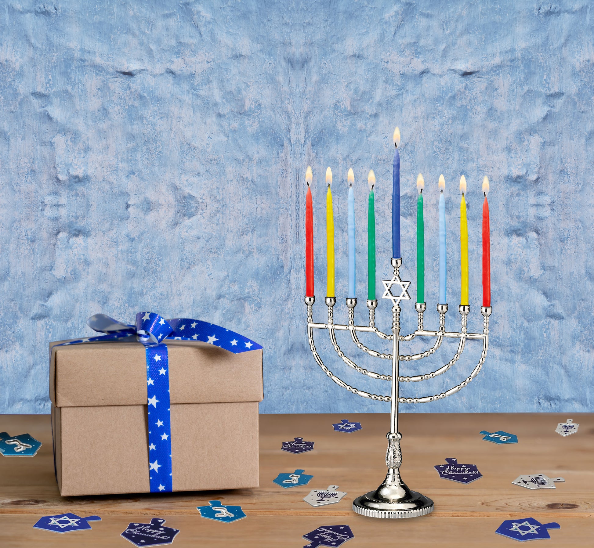Solid precision die cast classic polished silvertone menorah with candles lit next to Chanukah decorations
