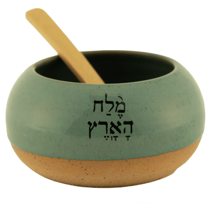 Sage ceramic salt bowl that says "salt of the earth" in English and Hebrew with a wooden spoon