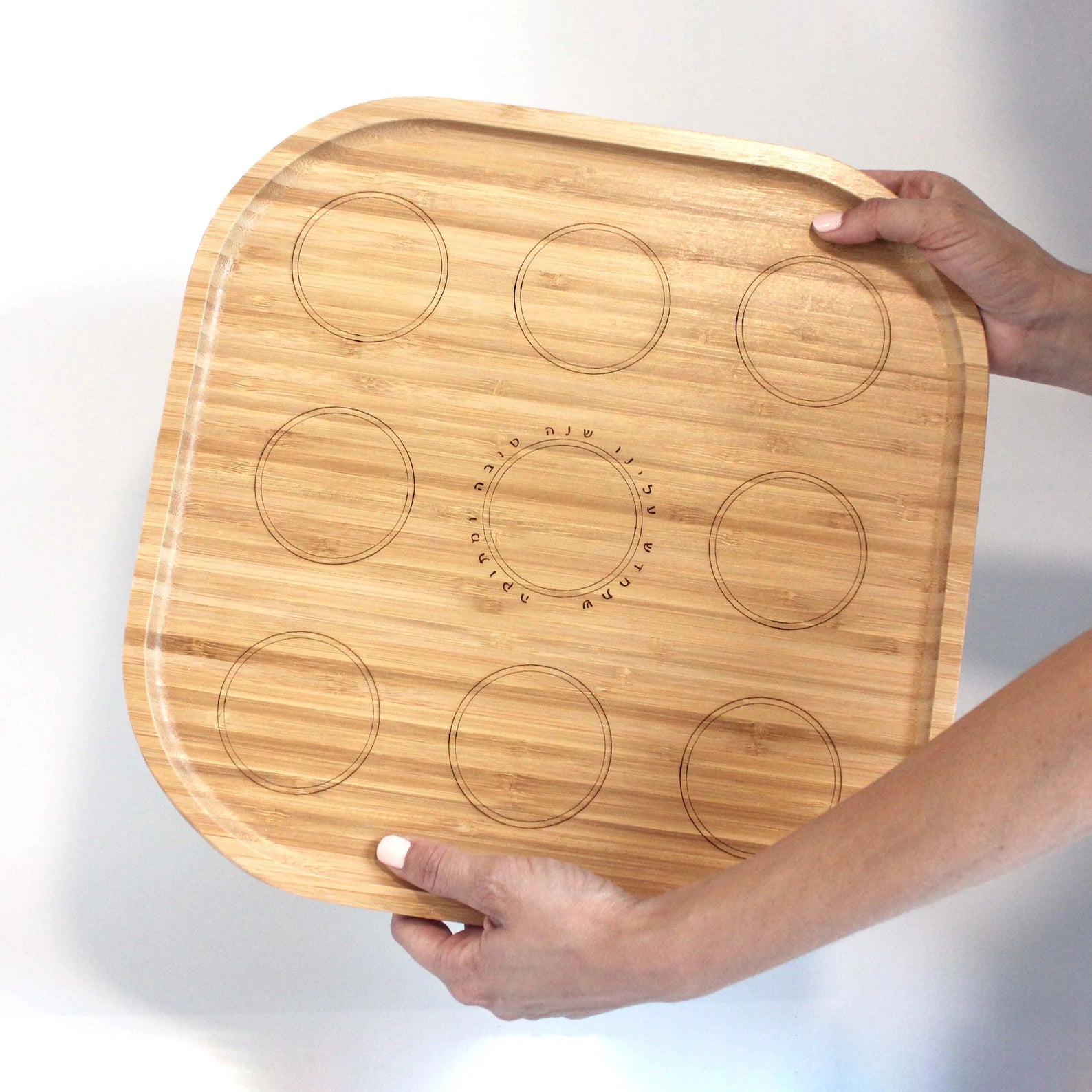 Two hands holding bamboo Rosh Hashanah plate
