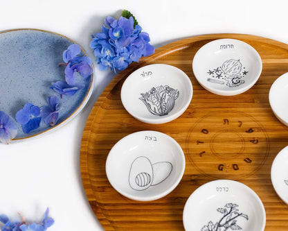 Closeup of Bamboo Passover Seder plate with porcelain bowls featuring black and white illustrations 