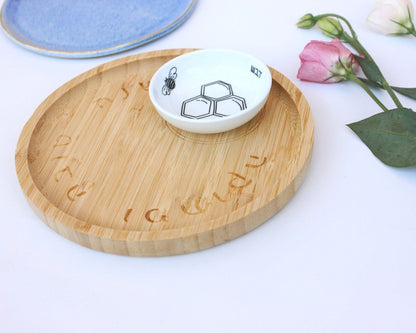 Porcelain bowl with a delicate black and white illustration of a bee and honey and a bamboo tray