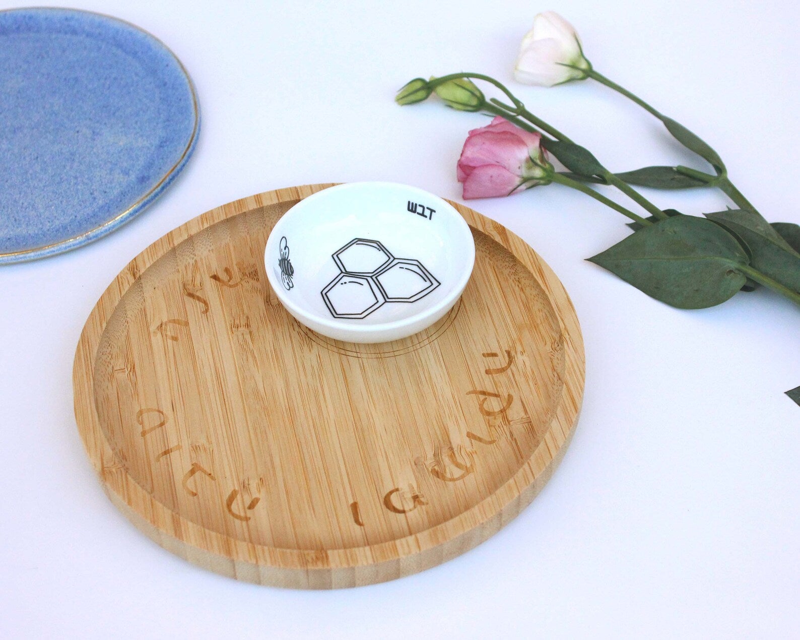 Porcelain bowl with a delicate black and yellow illustration of a bee and honey and a bamboo tray shown at an angle