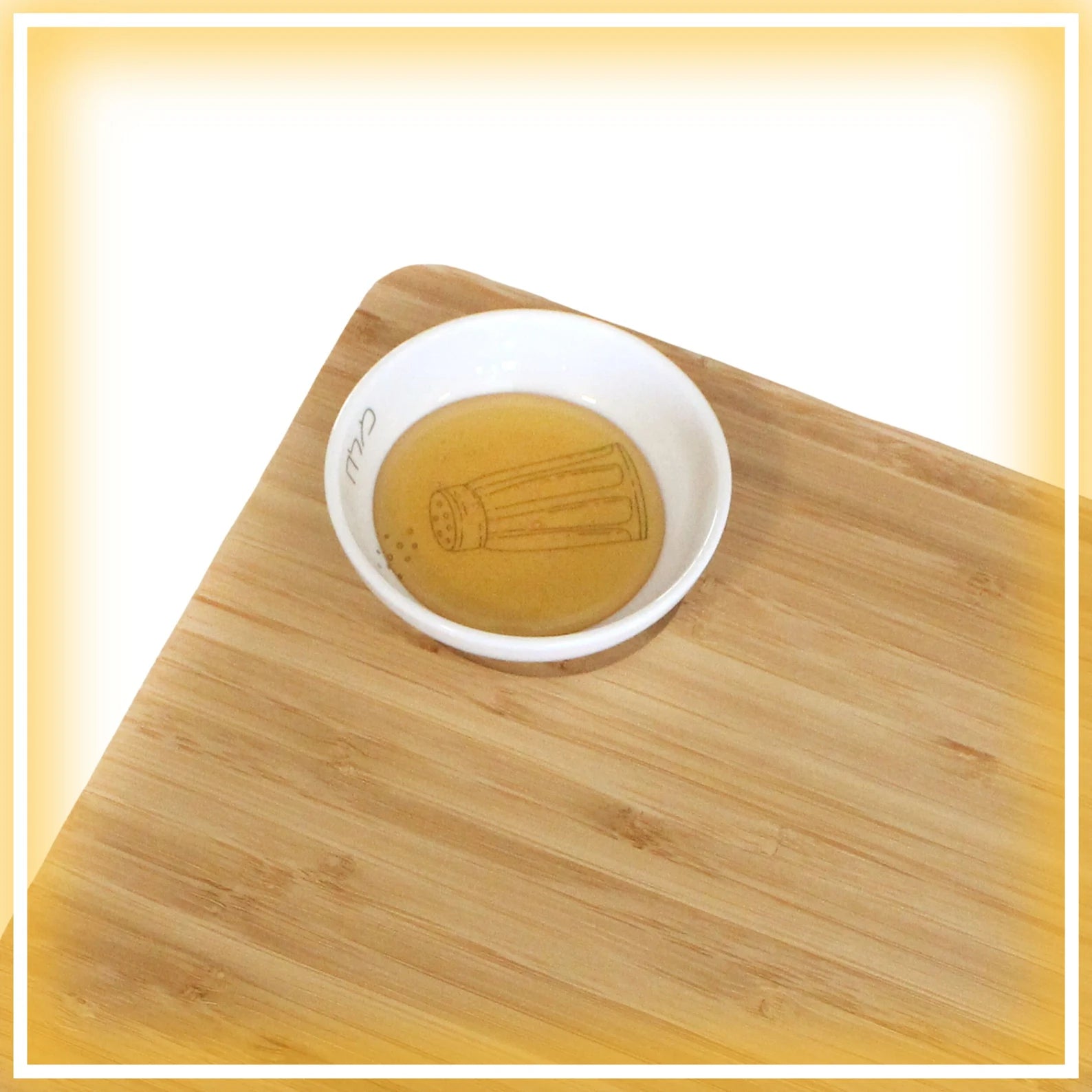 Porcelain bowl which features an illustration of a blue and white salt shaker on the Bamboo Challah Board with honey in the bowl