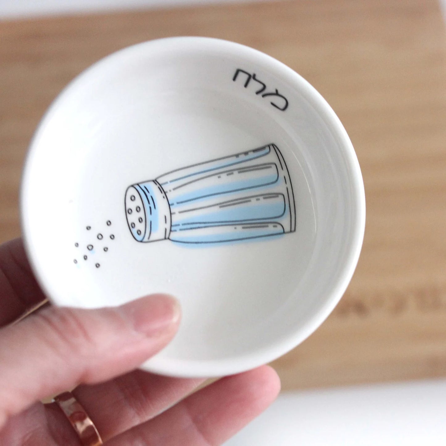 Porcelain bowl which features an illustration of a blue and white salt shaker 