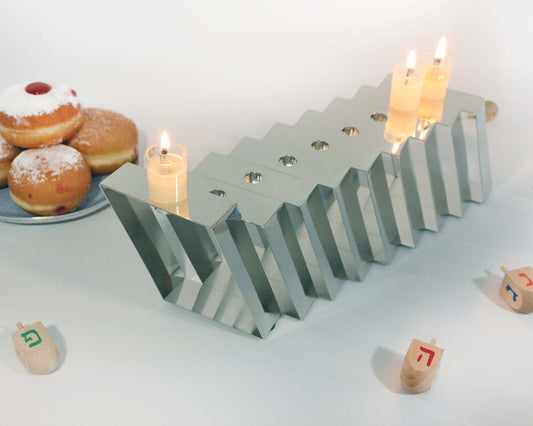 Silver Hanukkiah with three lit candles shown from the top