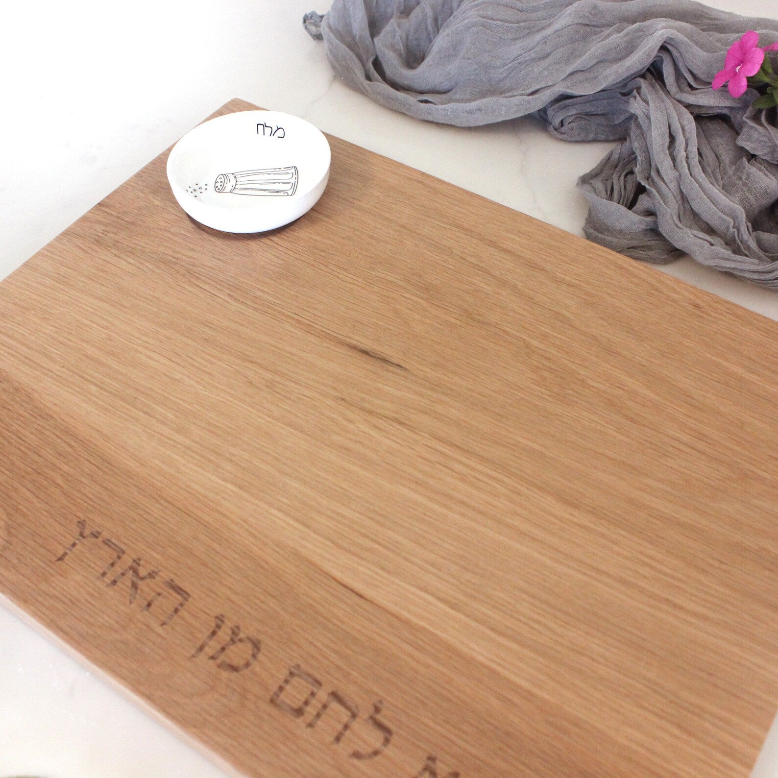 Close up of an Oak Challah Board with a porcelain bowl which features an illustration of a black and white salt shaker with honey in the bowl