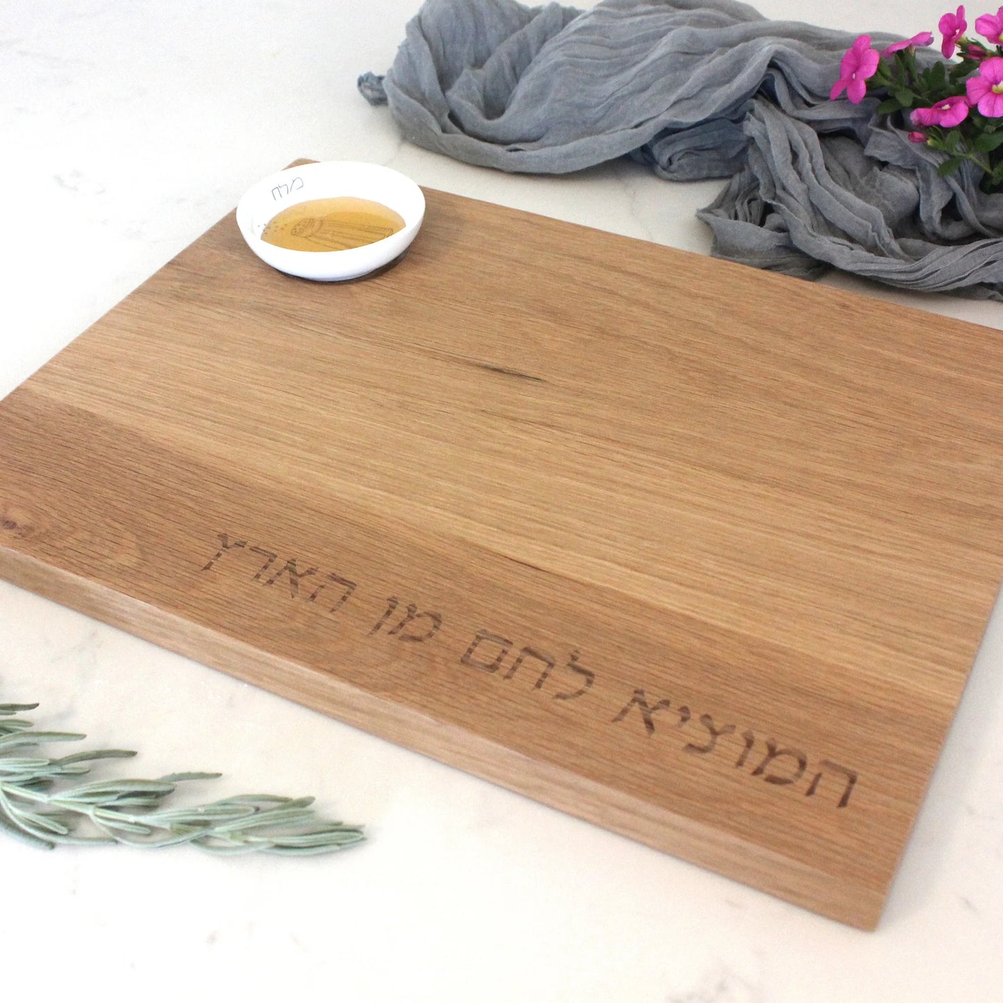 Close up of the Oak Challah Board with a porcelain bowl which features an illustration of a blue and white salt shaker with honey in the bowl
