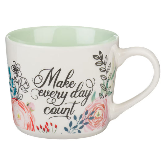 White floral mug with green interior and motivational quote in white script