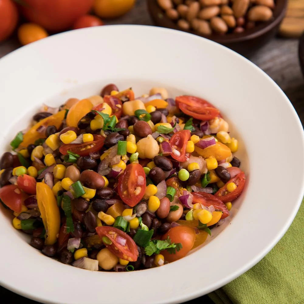 assorted vegetables such as tomato beans corn onion and herbs in white bowl