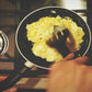 scrambled eggs being cooked in frying pan with spatula 