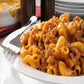 chili mac up close in white bowl with silver fork on the side 