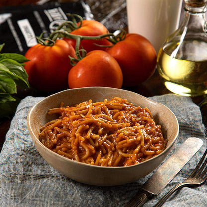 spaghetti with red sauce in bowl with cutlery on right side 