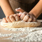 who hand needing dough in flour on wooden surface 