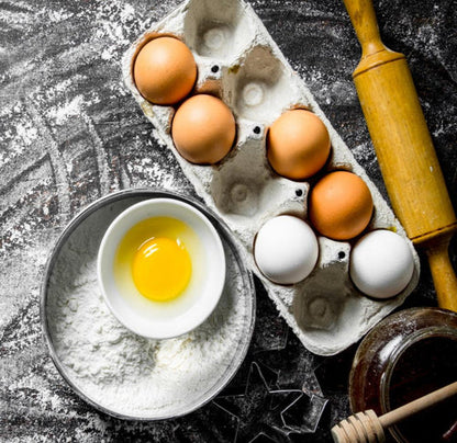 half full carton of eggs with egg yolk and powder in bowl on left and honey and roller on right 