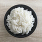 long grain white rice in black bowl with grey background