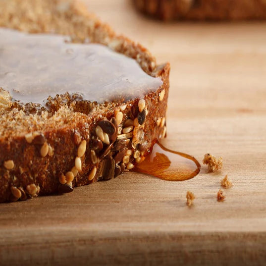 up close image of honey wheat bread with honey dripping off of bread 
