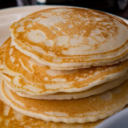 stack four high of buttermilk pancakes on white plate 