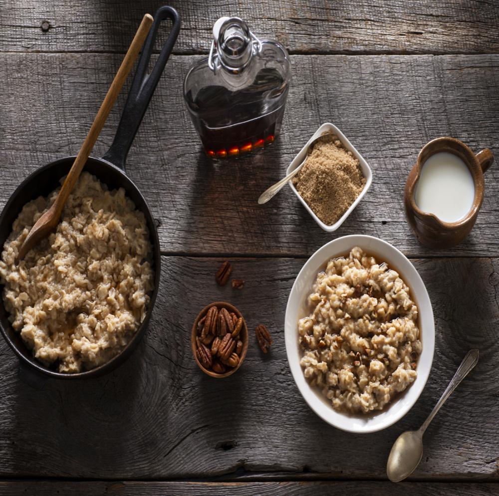 maple grove oatmeal in deep pan with wooden spoon bowl of walnuts brown sugar maple syrup cream dish
