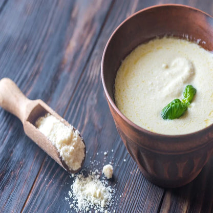 white sauce with green garnish on top in wooden bowl with parmesan cheese 