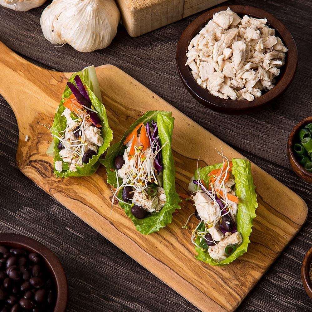 lettuce wrapps with diced chicken on wooden cutting board 