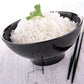 long grain white rice with green garnish on top in black bowl with black chopsticks on the side 