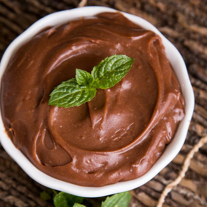 chocolate pudding with green garnish on top in white dish